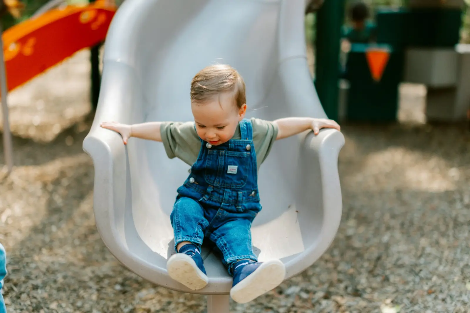 Un enfant sur un toboggan, cadré sur les jambes.